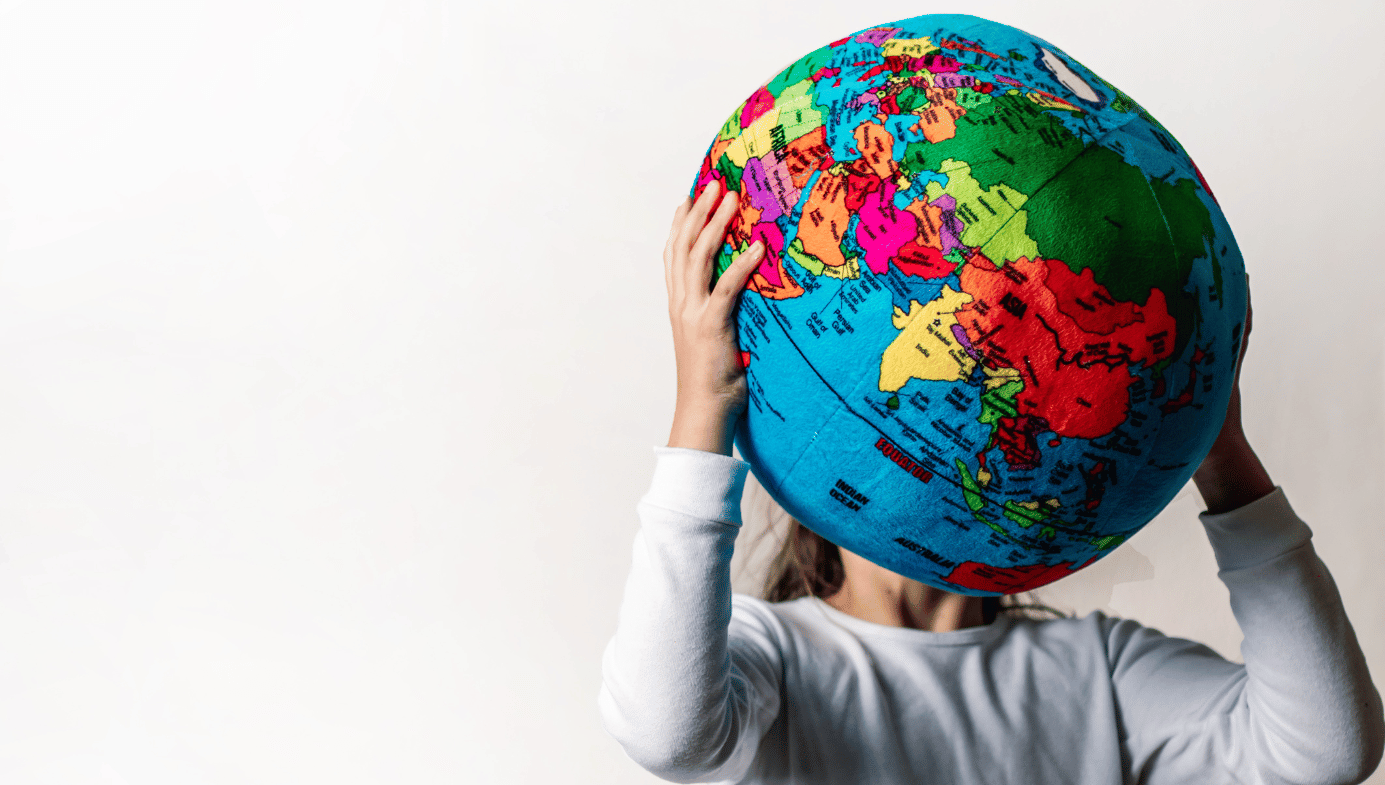A child holding a world globe in front of them. 