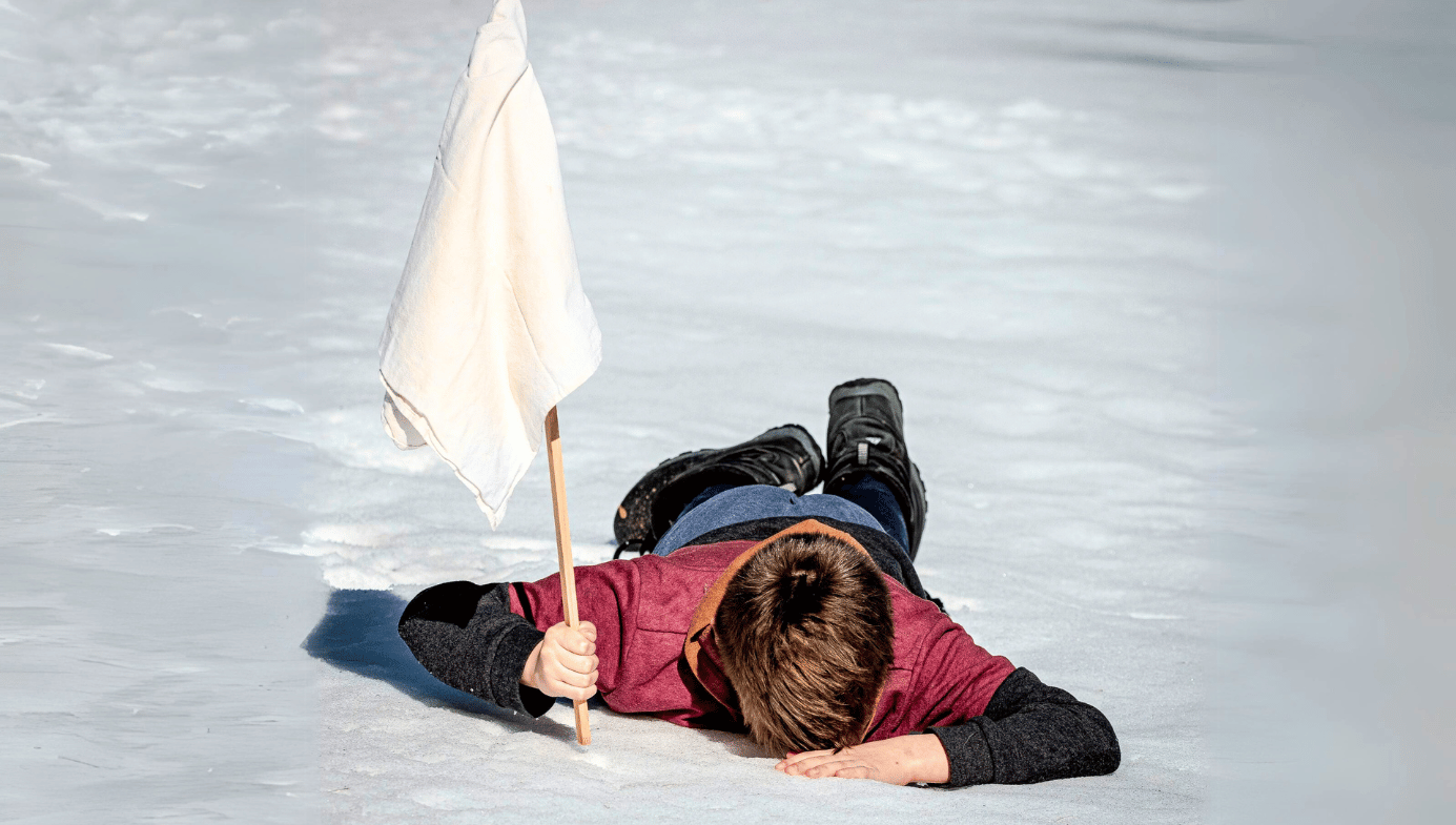 A child face down in the snow having a tantrum and planting a white flag of surrender.