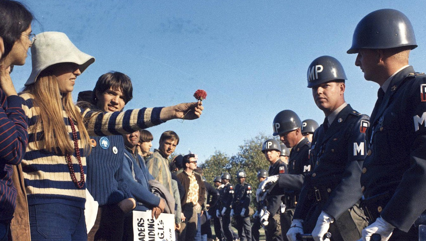 A female demonstrator offers a flower to military police on guard at the Pentagon during an anti-Vietnam demonstration