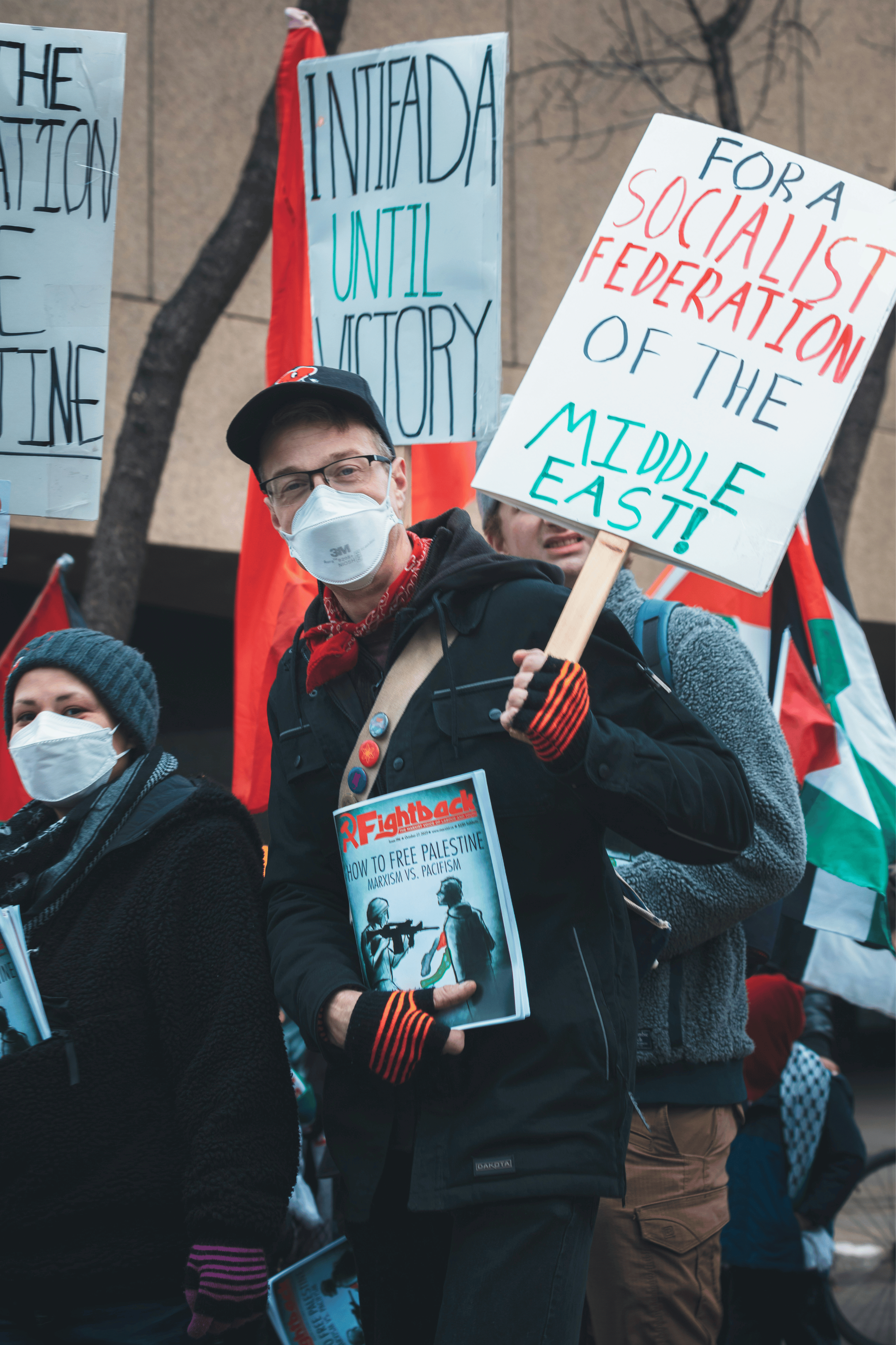 Manifestantes enmascarados a favor de Palestina con lemas comunistas y una revista comunista