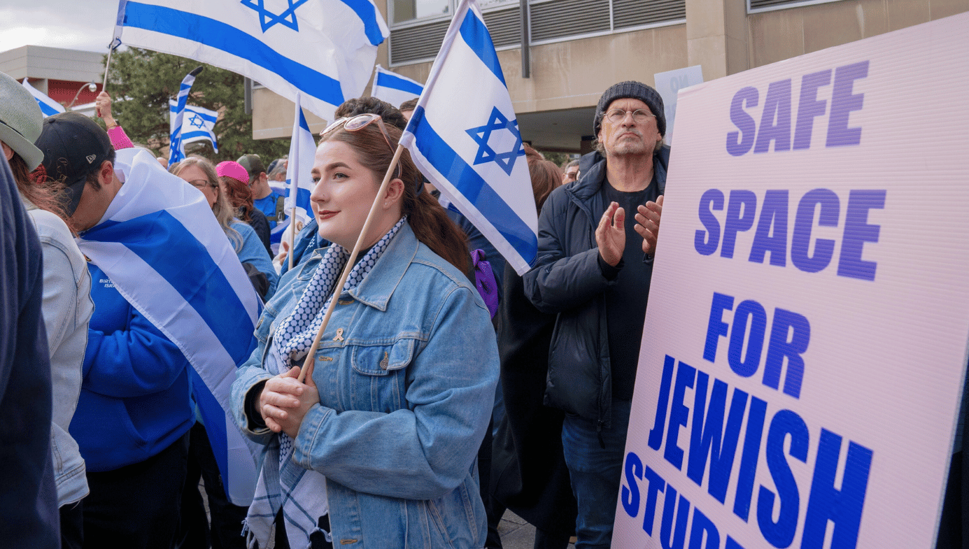 Students holding Israel flags in front of a banner stating "Safe Space for Jewish Students."
