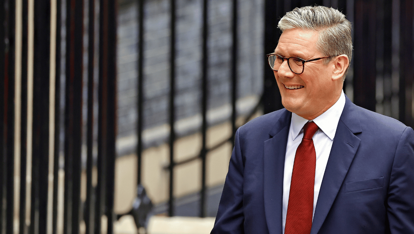 Sir Keir Starmer arrives at Downing Street. He's smiling, in a red tie, blue suit. 