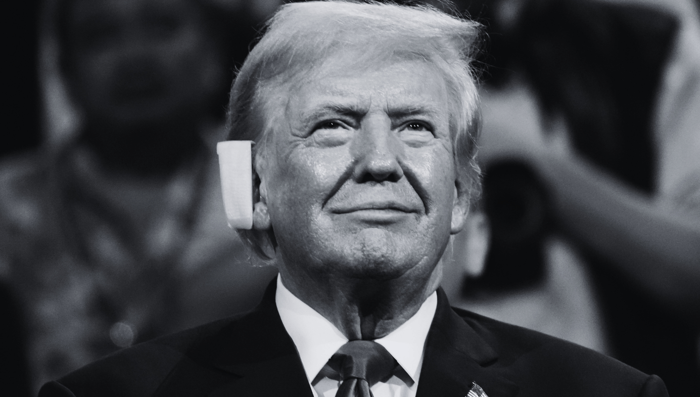 Donald Trump, smiling, with a large bandage over his right ear. 