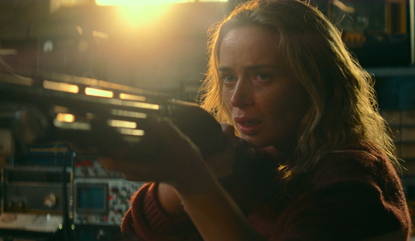 Actress Emily Blunt pointing a gun. 