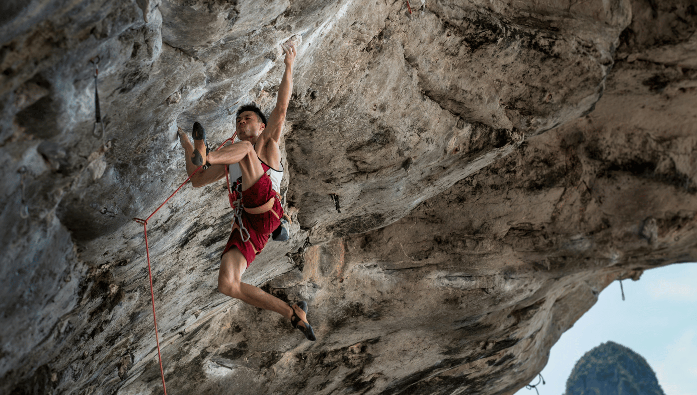 Male climber scaling a rock face. 