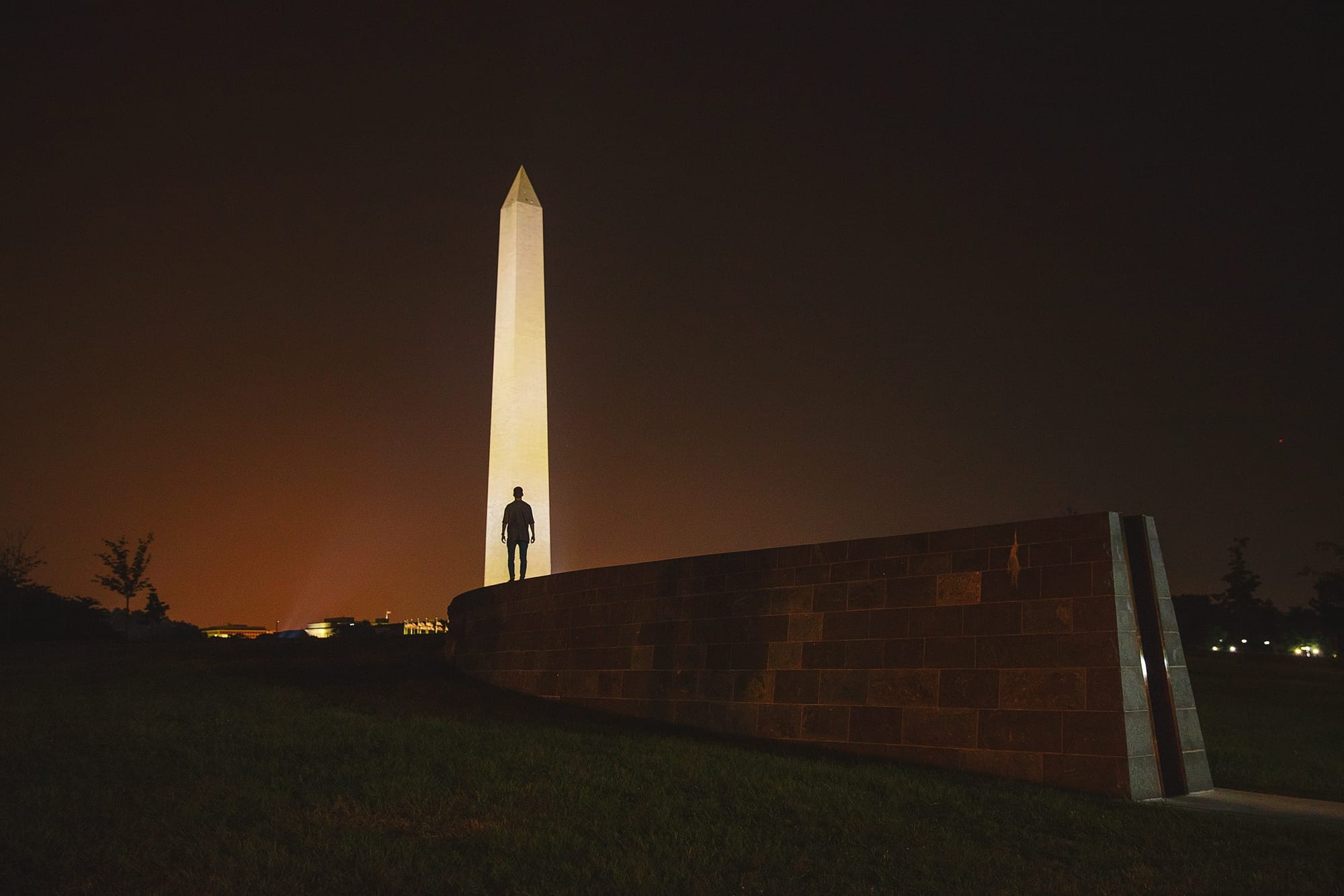 Man stands in front of a lighted obelisk.