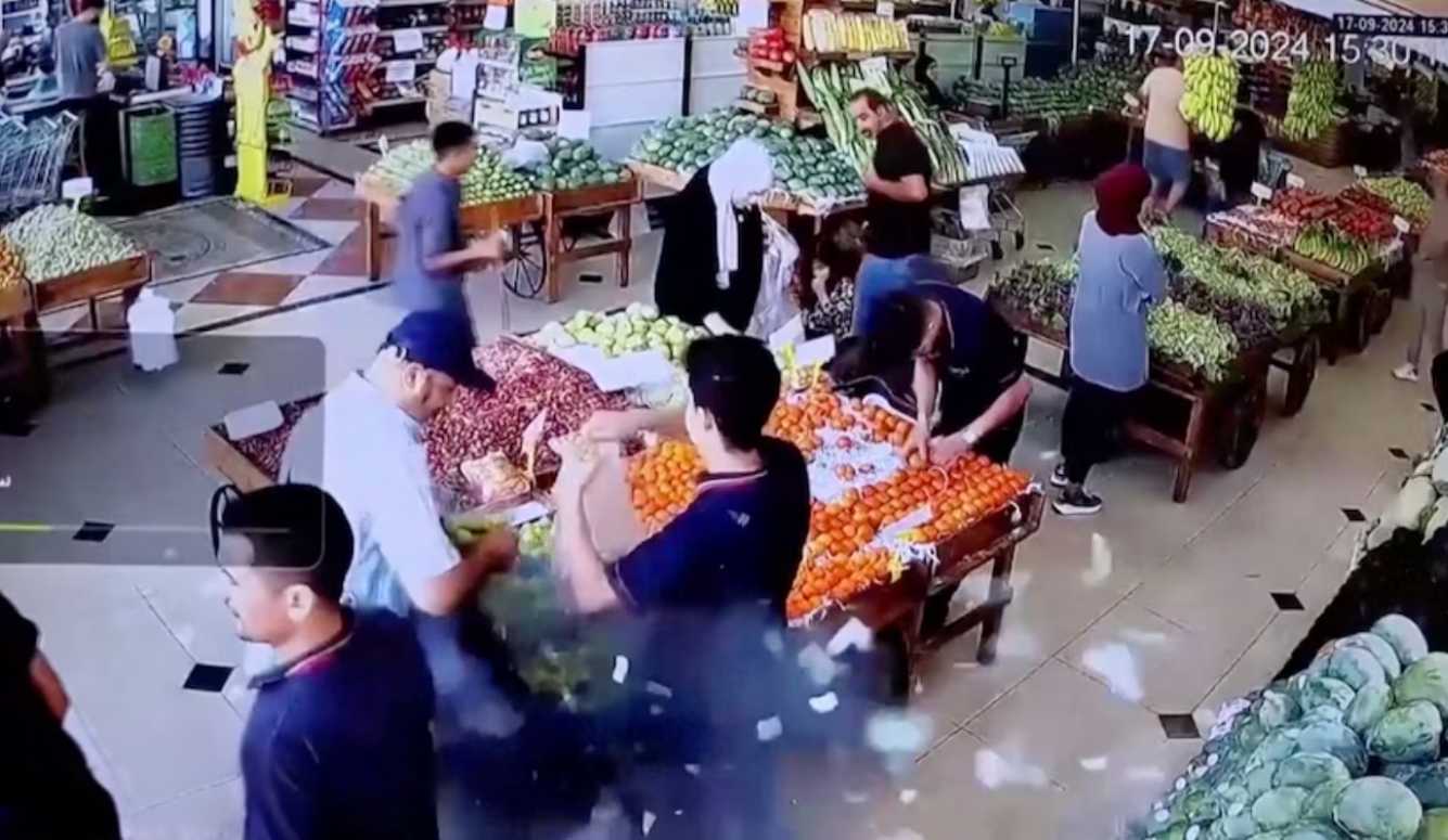 CCTV footage screenshot of a pager exploding in its owner's hands in the produce section of a supermarket. 