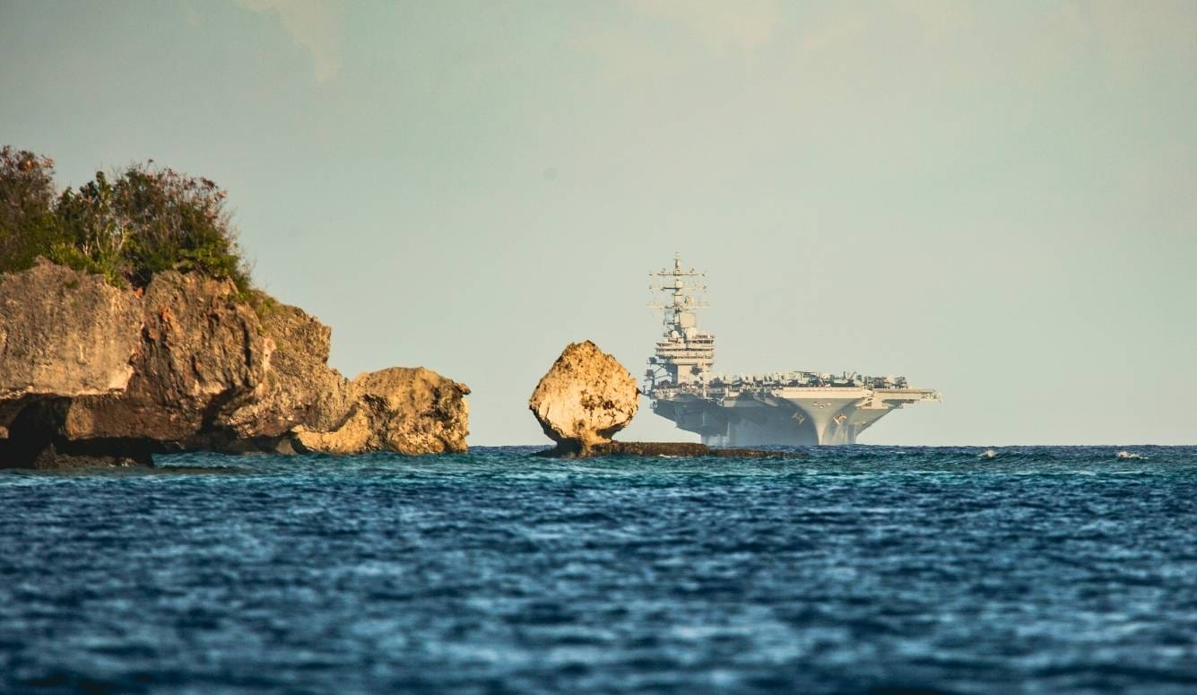 A huge naval base on the water next to a cliff in Guam.