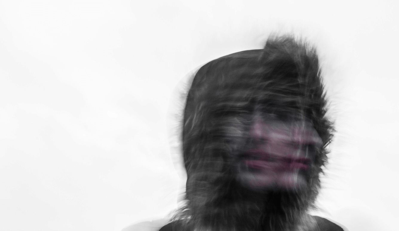 A creepy blurred photo of a person's face and a furry hood.