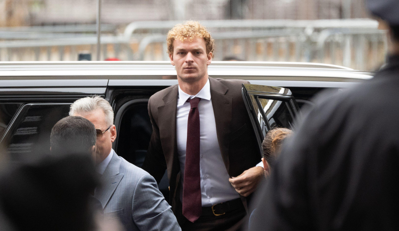 Daniel Penny is a tall man in his 30s, with curly blonde hair. He is getting out of a car, wearing a suit. 