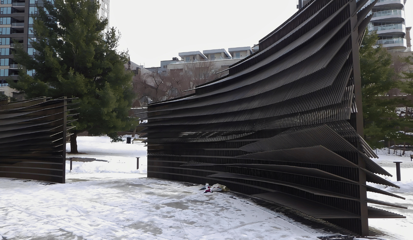 The memorial is a big black wall. Snow is on the ground. 