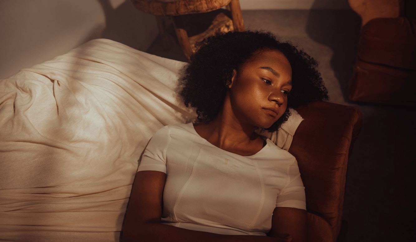 Woman resting on couch with light coming n looking sad.