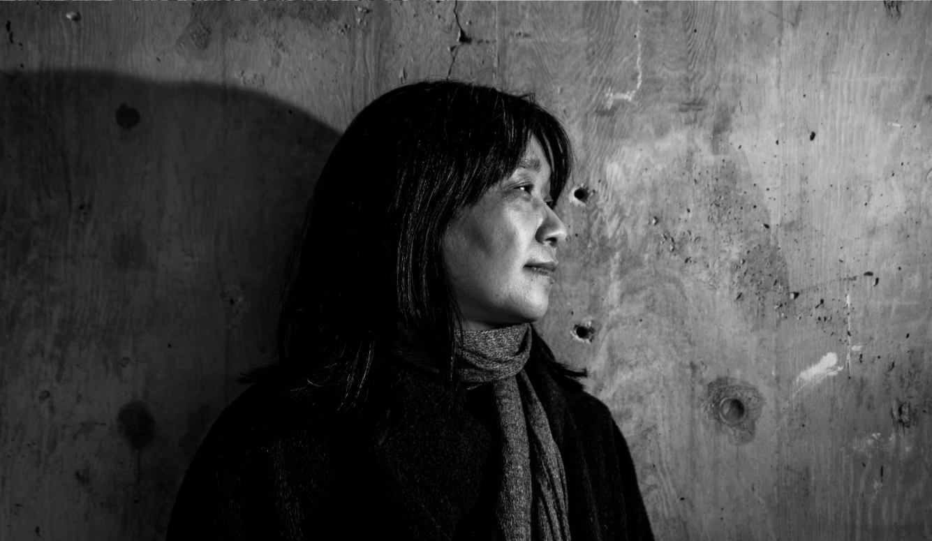 Black-and-white head-and-shoulders photo of the novelist, wearing a scarf, in profile. 