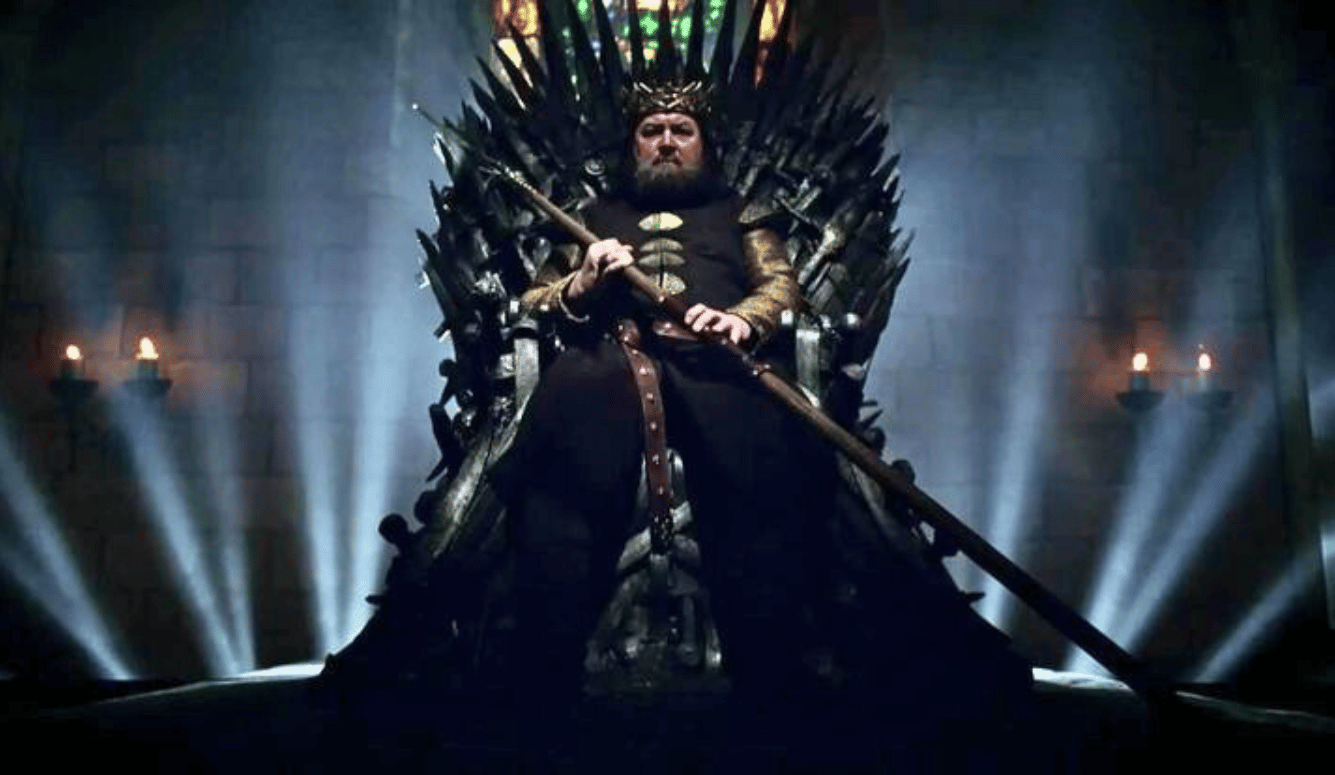 Mark Addy as Robert I Baratheon, seated on the Iron Throne. 