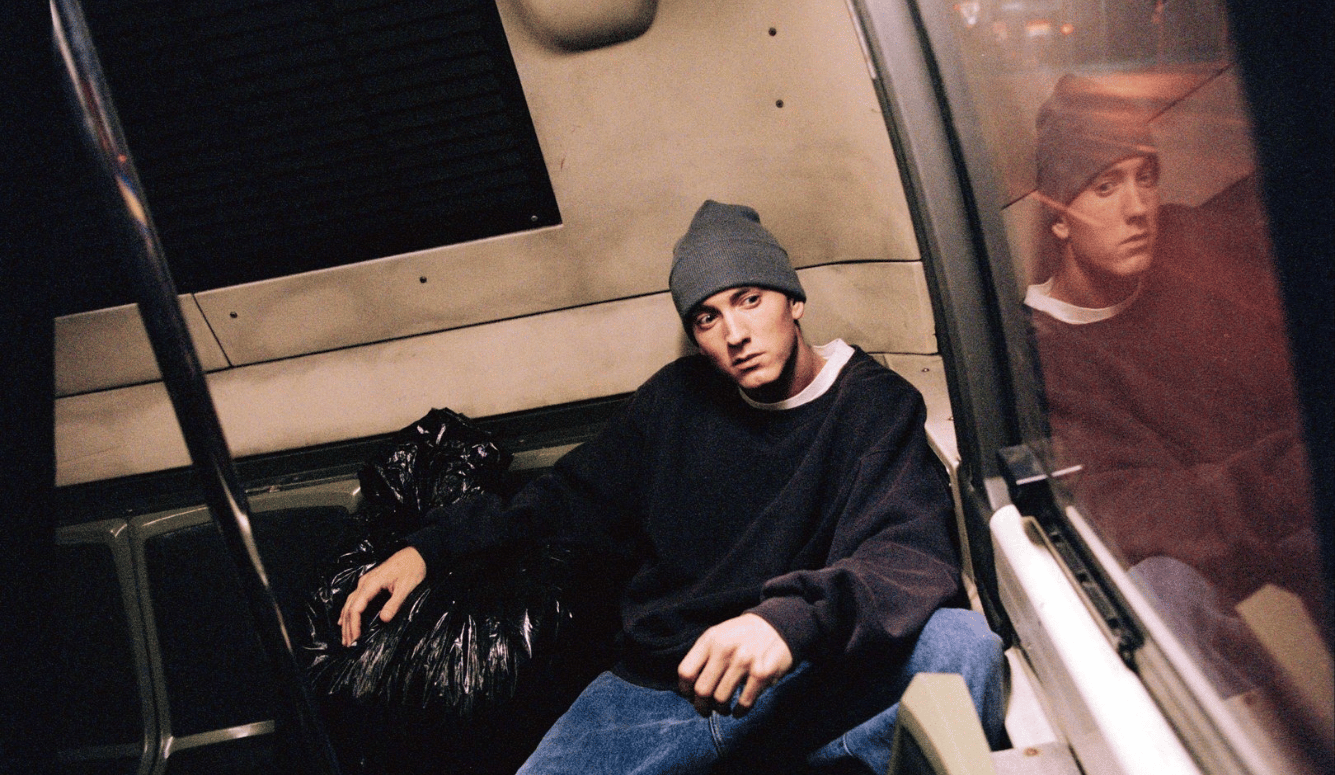 Eminem in a train carriage, holding a rubbish