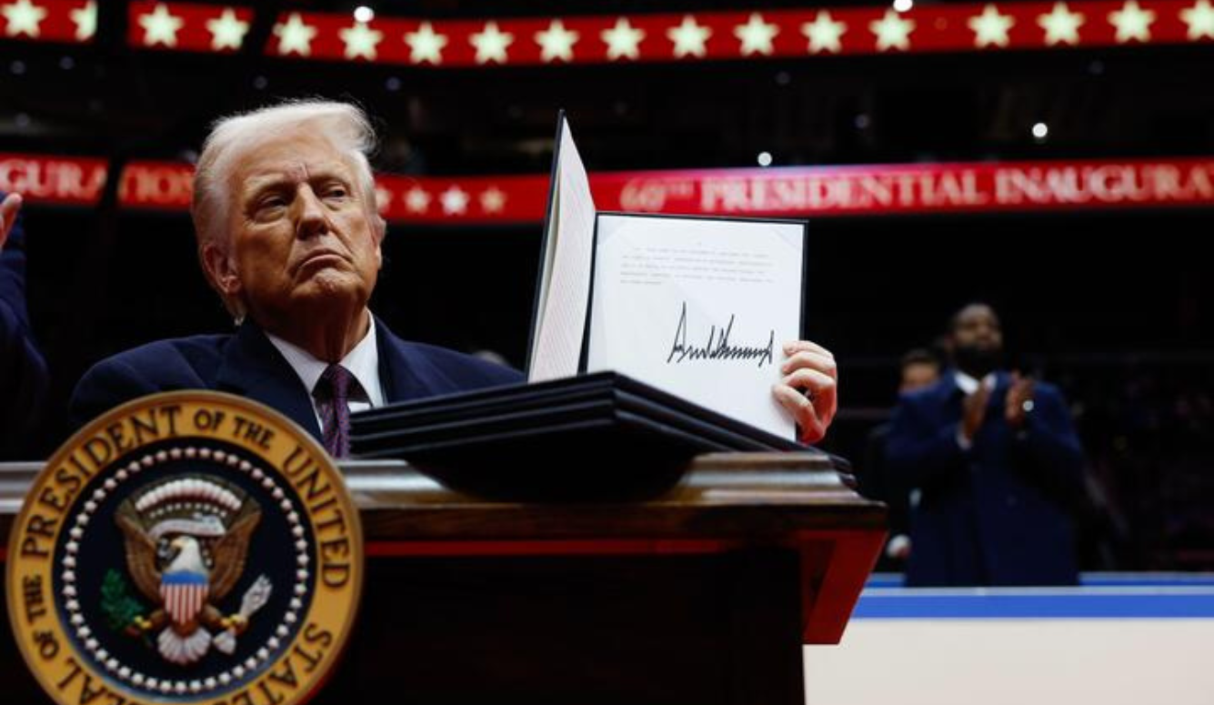 President Donald Trump holds up an executive order