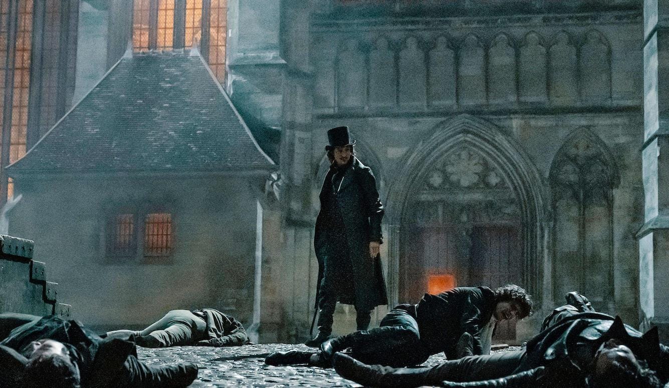 Scene from the film, with the Count in front of Notre Dame. In the foreground, dying men. 