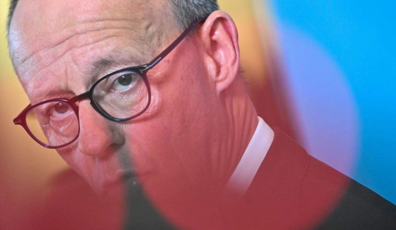 Friedrich Merz is a middle-aged white man with glasses. Seen here through a blurry lens. 