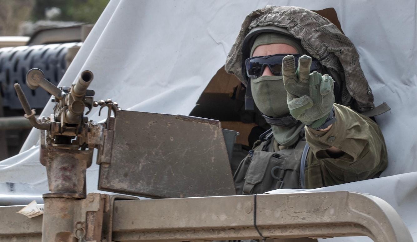 A soldier makes a hand gesture from the turret of a Humvee. 