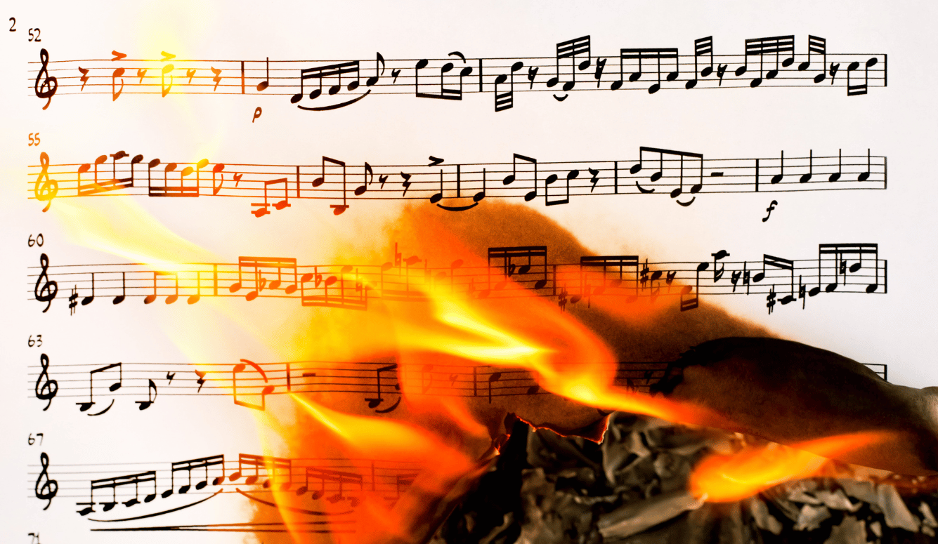 A sheet of music burns with orange flames.