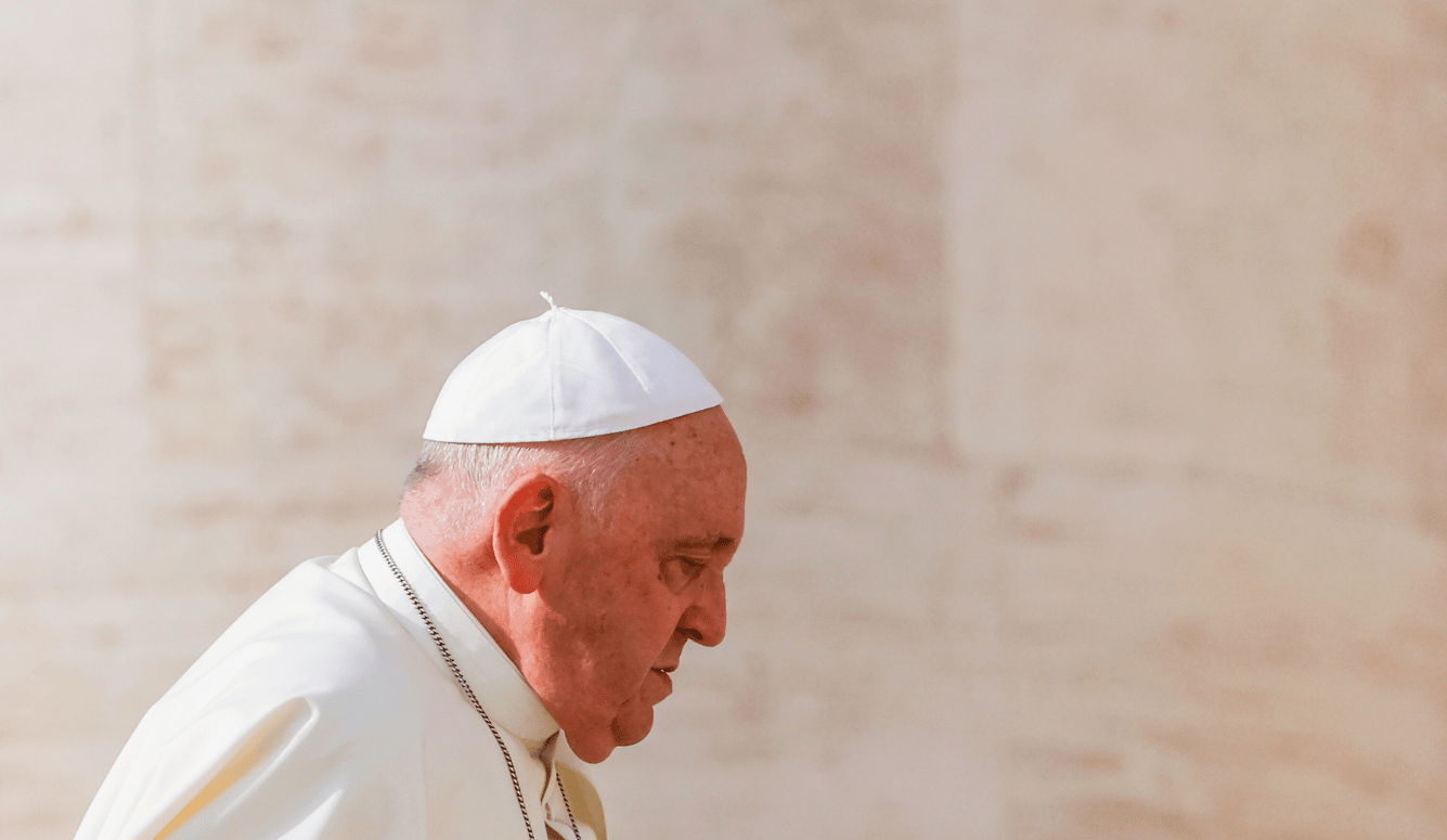 The profile of Pope Francis in a white skullcap.