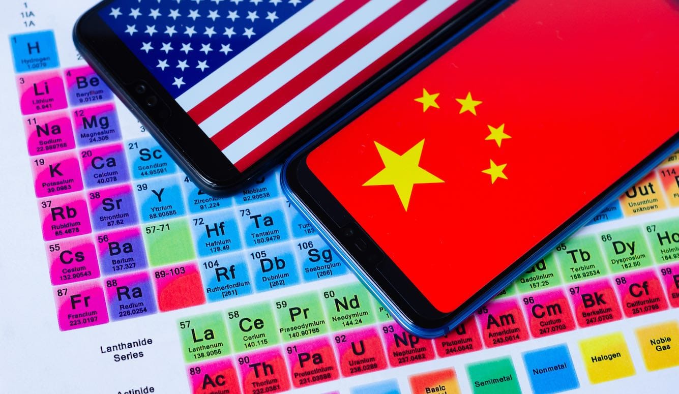 A periodical table. Two cellphones have been placed on top: one has the US and one the Chinese flag. 