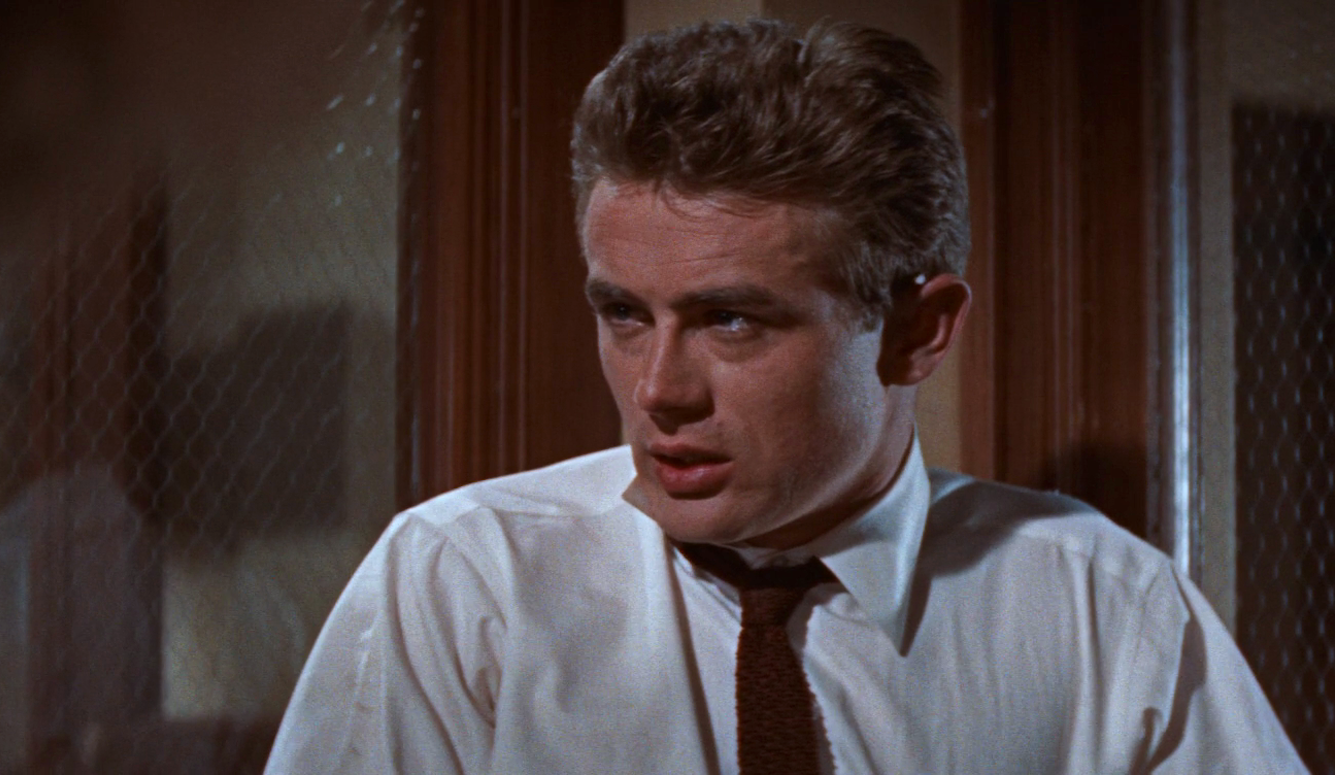 Still of James Dean, in a shirt and tie. He is a young white man with blonde hair. 