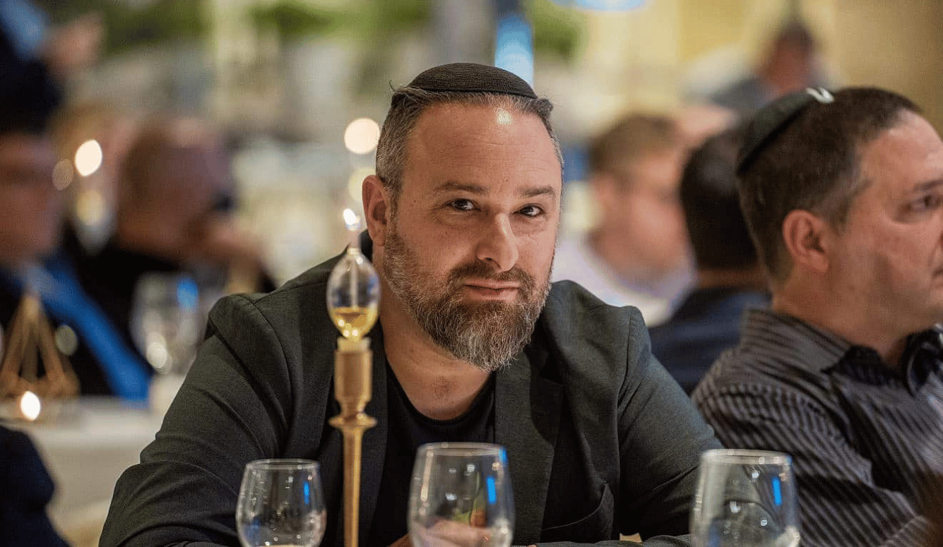 Hillel wears a black yarmulke and sits at a shabbat table.