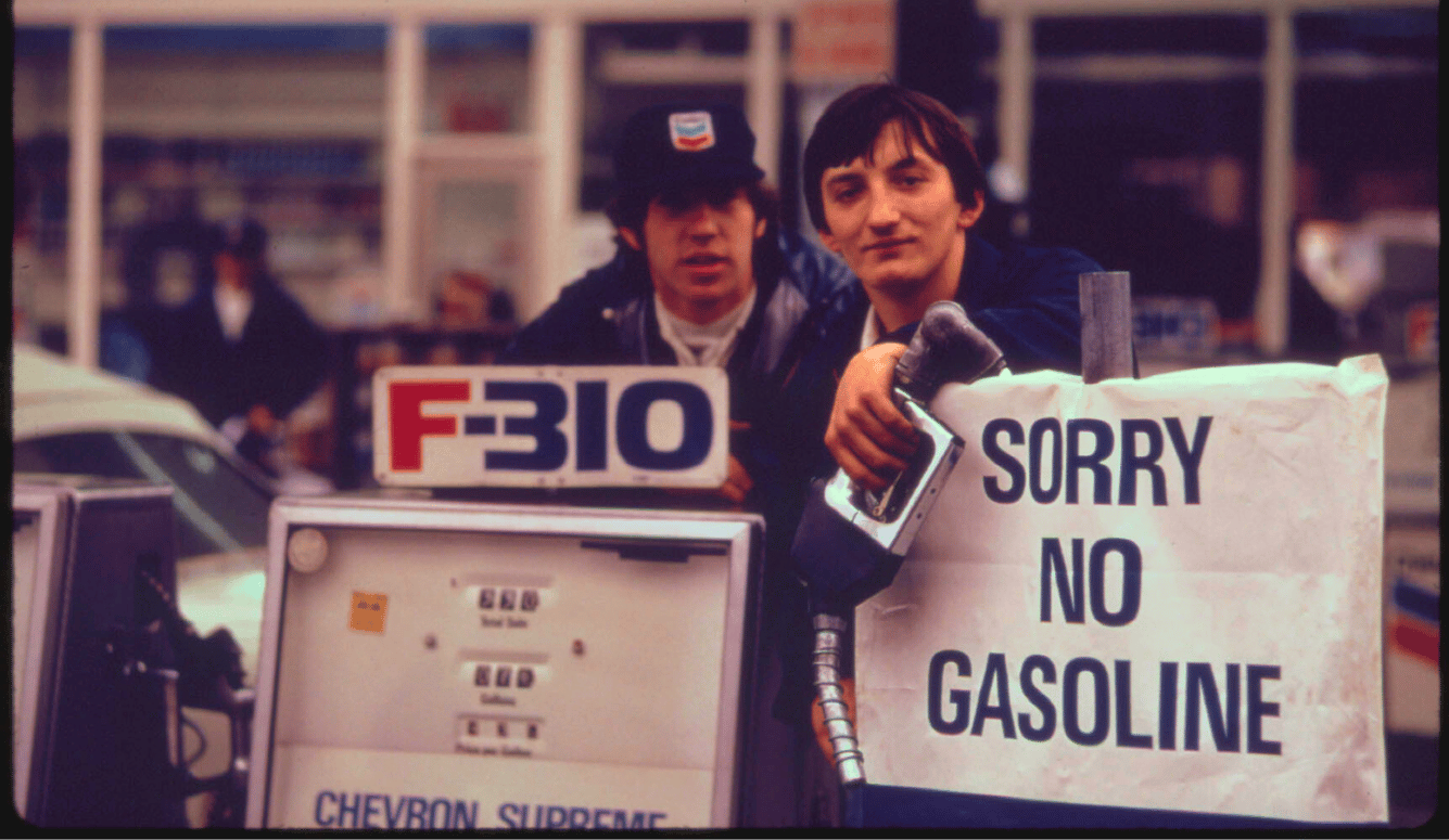 Gas station attendants look over an 'Out of Gas' sign