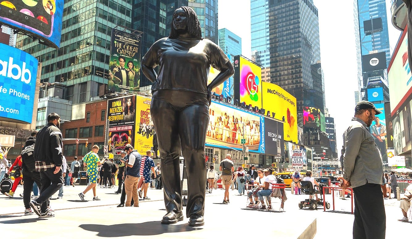A large statue of a woman with braids, in Times Square. 