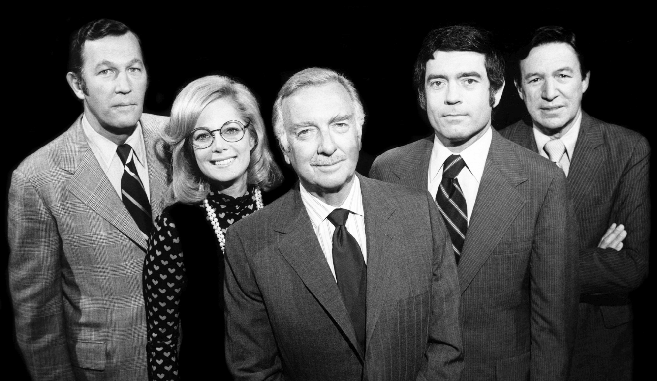 CBS Evening News staff: four men, one woman. The men wear suits and ties. Black and white image.