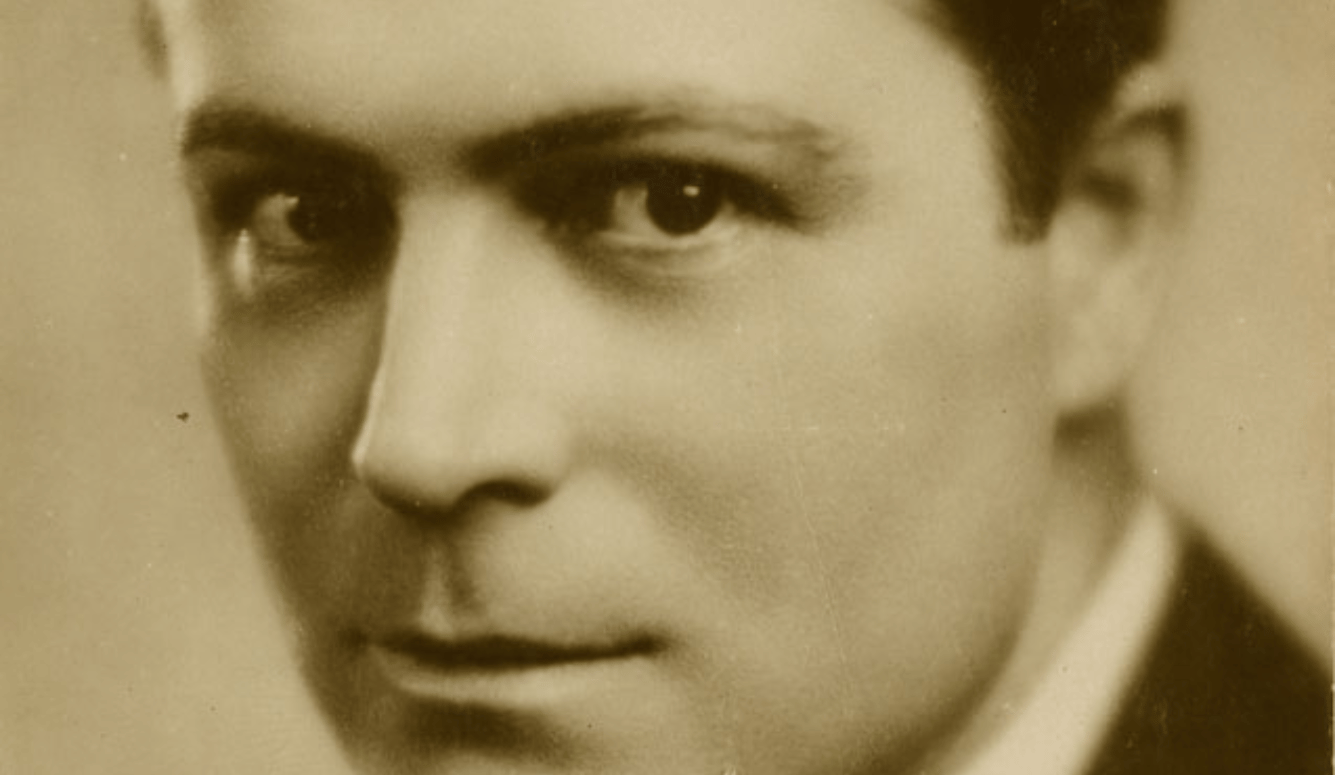 A sepia photo of a white man in close up. 