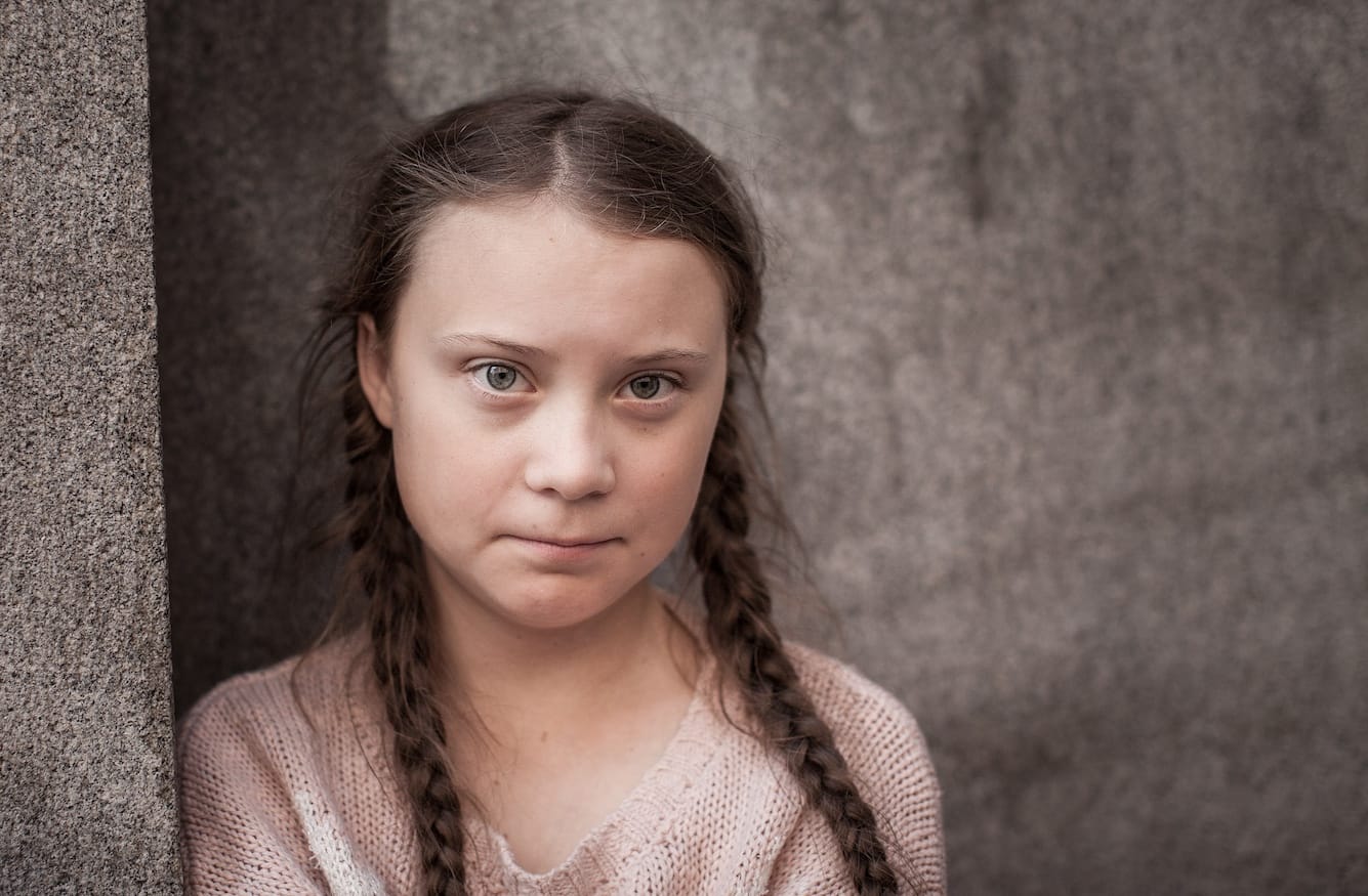 Greta Thunberg as a child. She has pigtails, pale skin and looks at the camera wryly. 