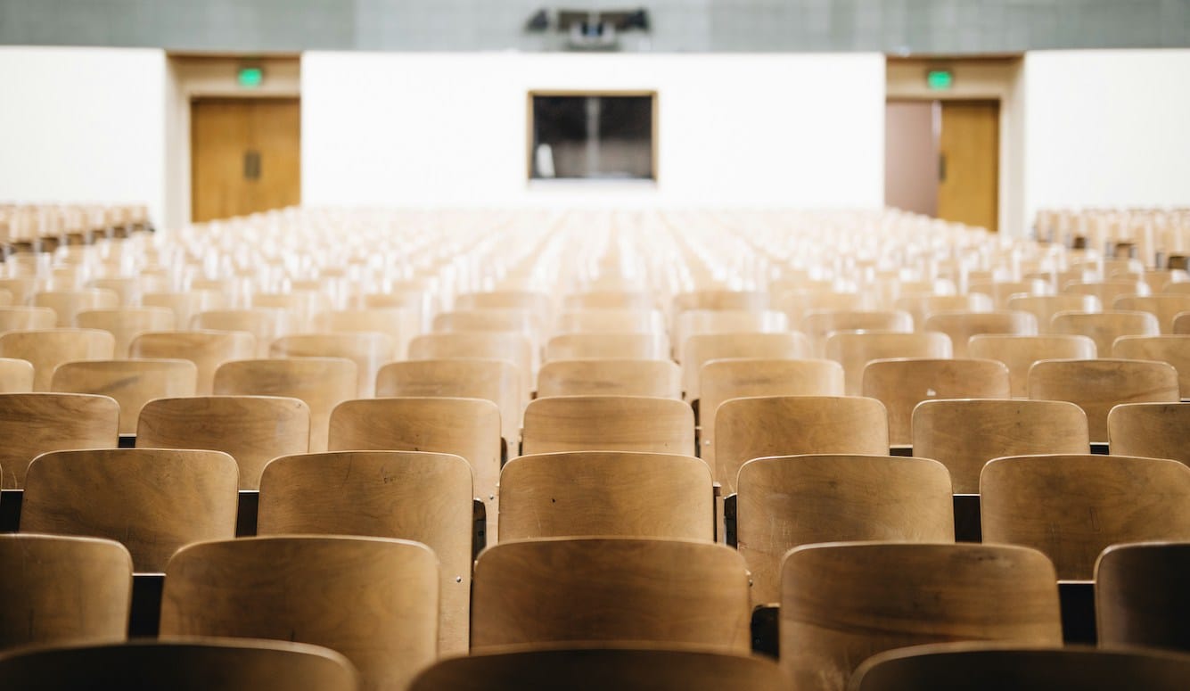 Rows of empty wooden seats in a lecture theatre. 