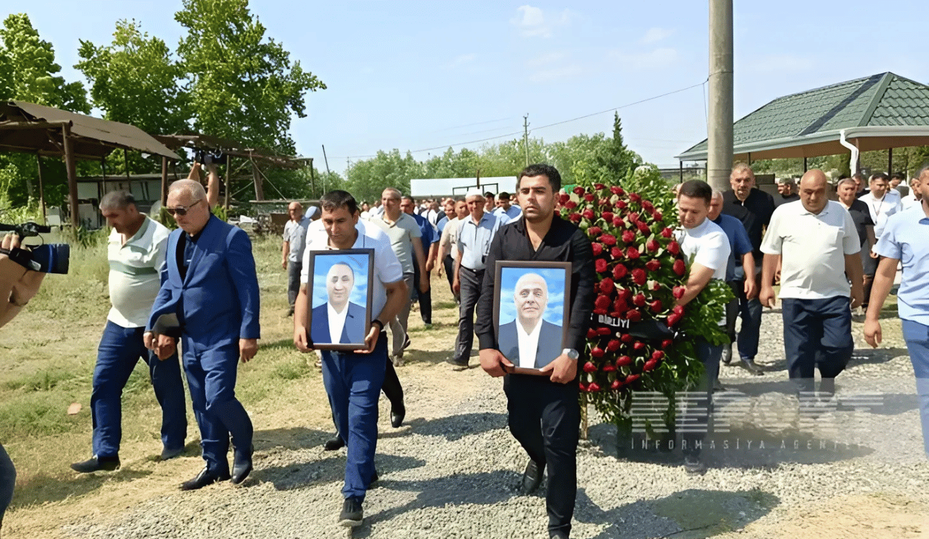 Men at funeral hold portraits of two dead men and a coffin covered in red roses.