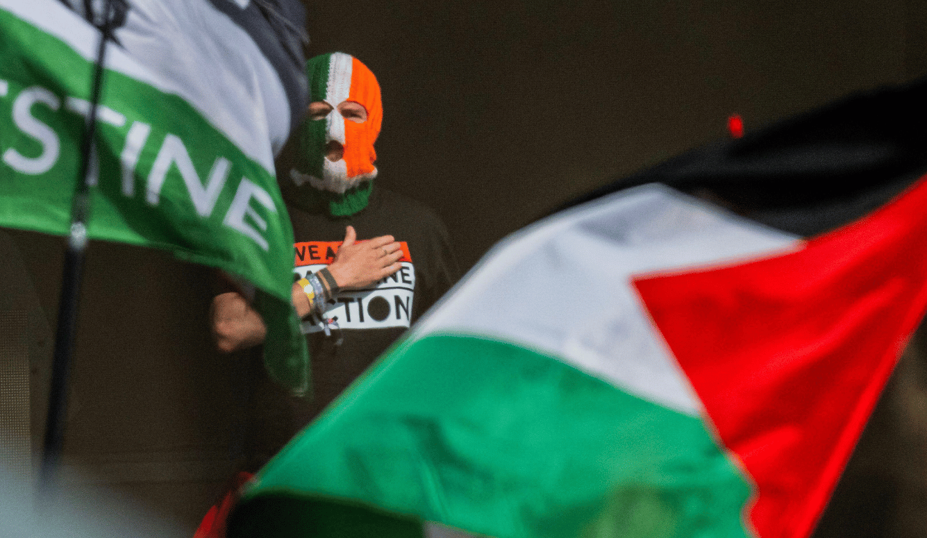 A man in Irish flag balaclava and Palestine flag.