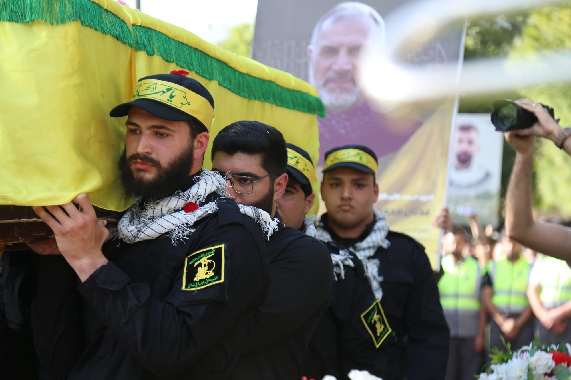 Hezbollah members carry the yellow flag-draped coffin of a senior official during his funeral in southern Lebanon. 