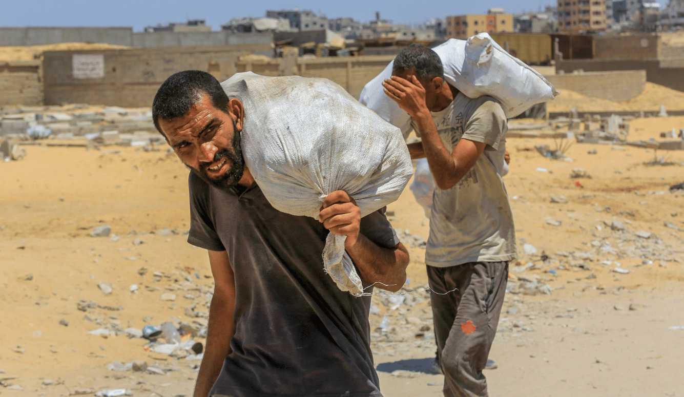 Palestinians carrying food aid they received from a US aid point in Rafah walk along a street in Khan Yunis, southern Gaza Strip, on 31 July 31 2025.