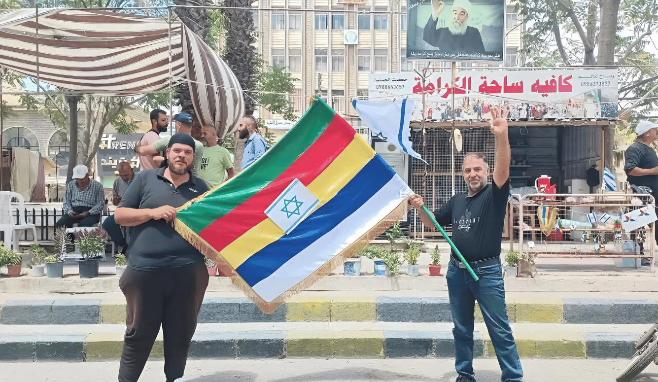 Druze men hold the Druze and Israeli flags at a protest in Suwayda, Syria on 2 August 2025.