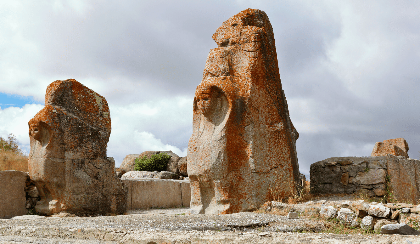 Two weathered stone lion sculptures at the gates of Hattusa, the Hittite capital in Turkey, showcasing the artistry and symbolism of the Late Bronze Age.
