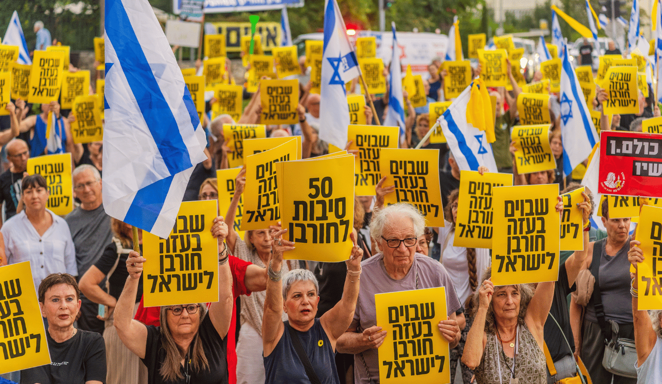 Crowd of people with protest signs: Hostages in Gaza destruction to Israel