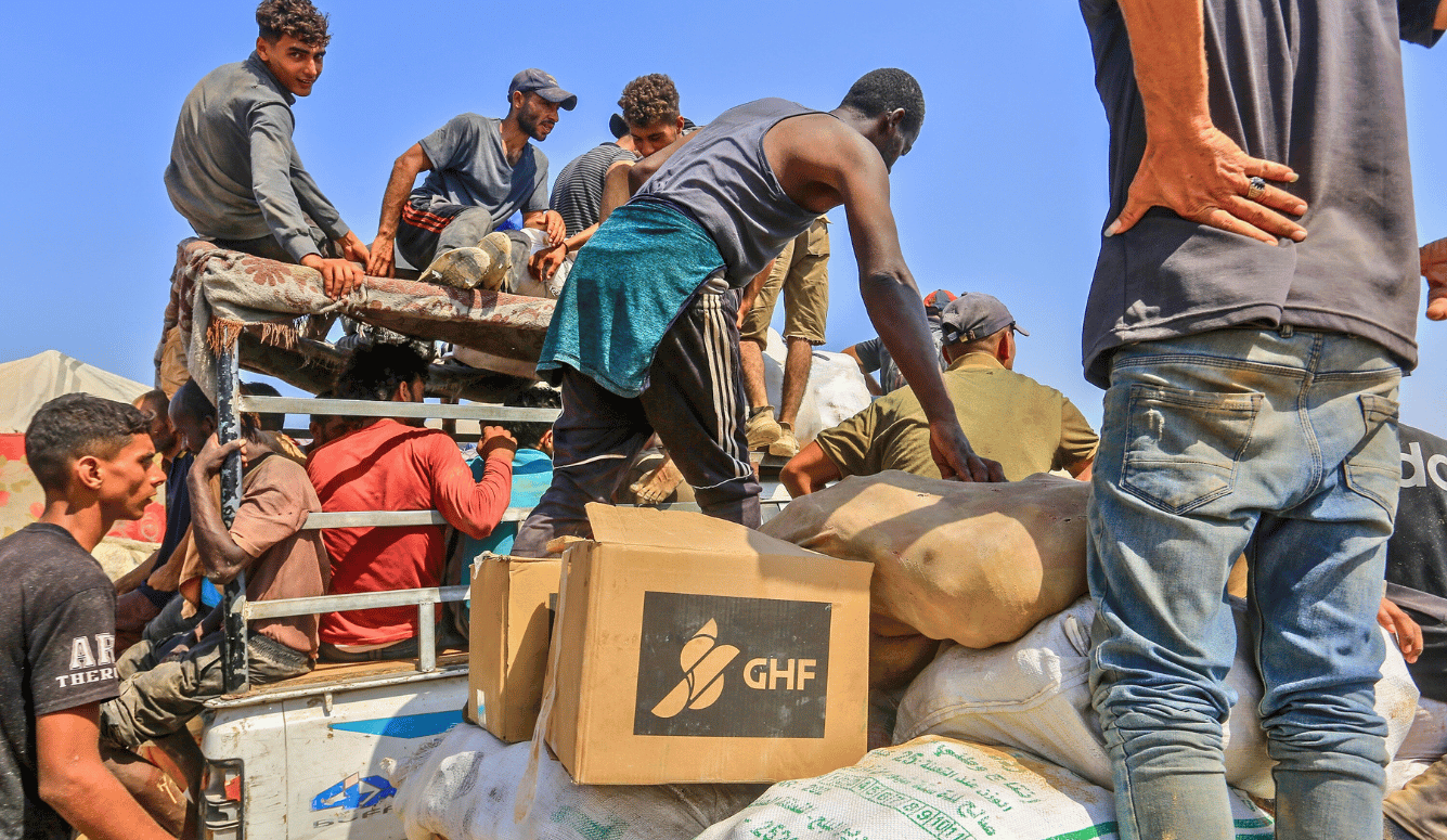 Palestinian men climb atop aid bundles.