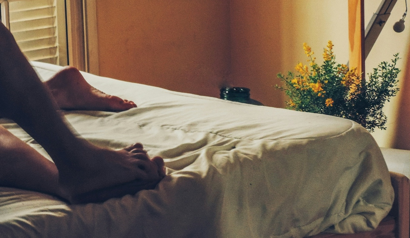 Two male feet in bed, suggesting sex.