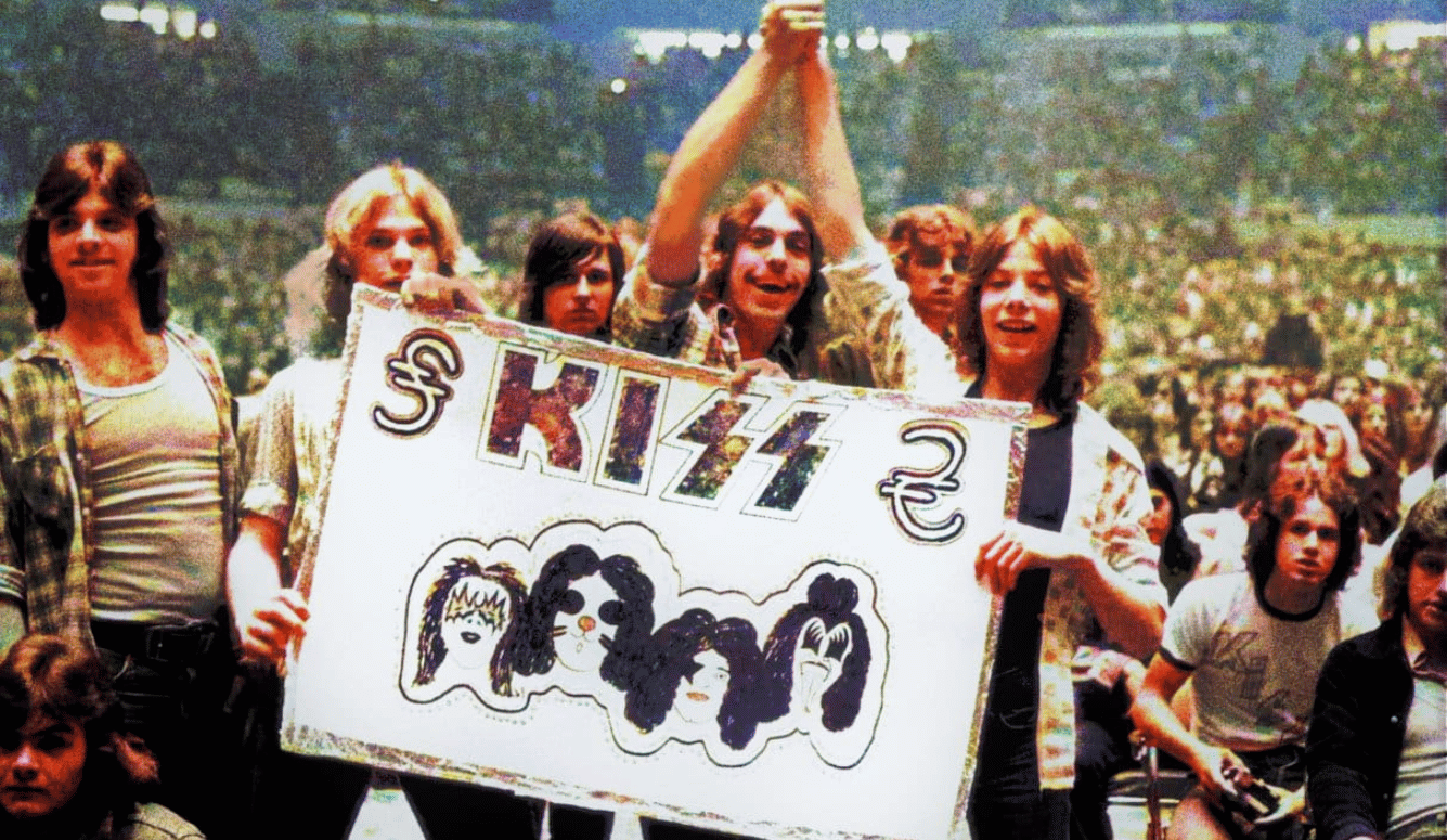 Young male fans with hand drawn sign that says KISS.