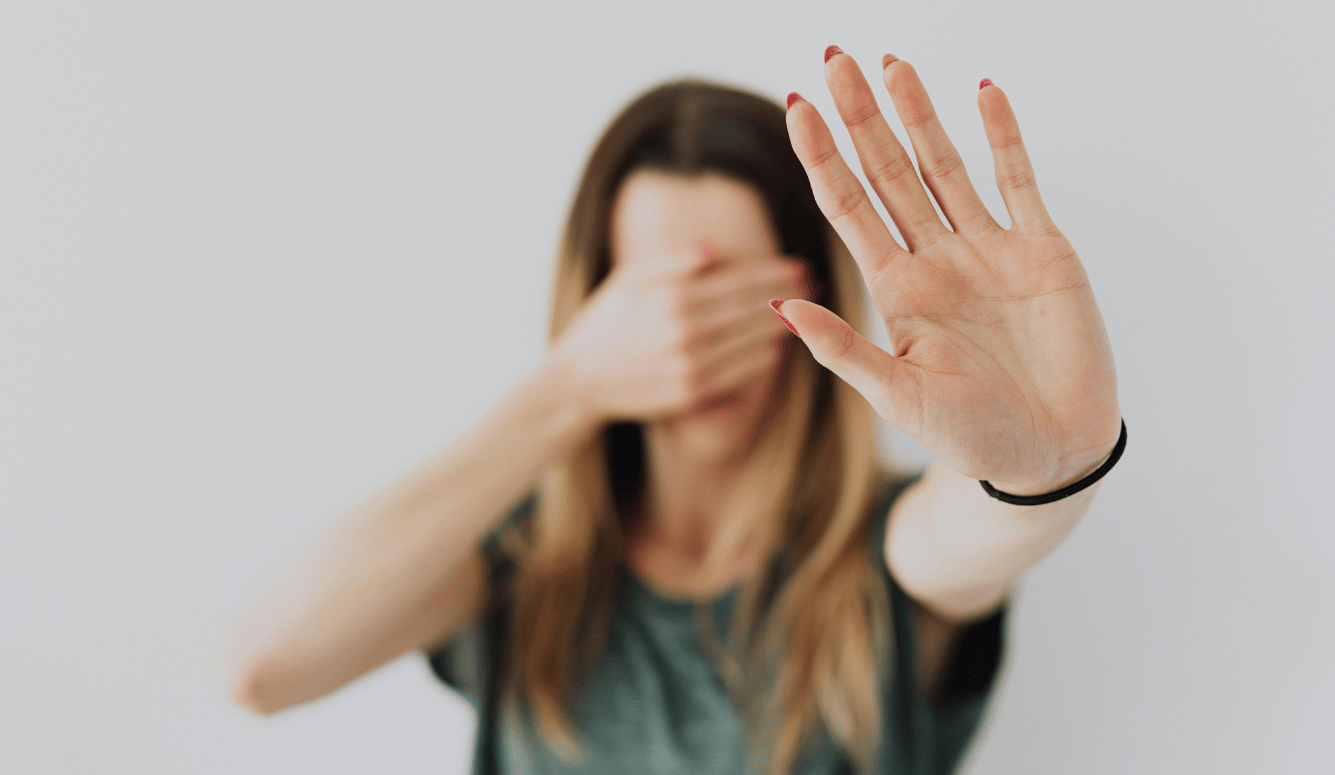 A woman covers her eyes and raises a palm "no more speaking".