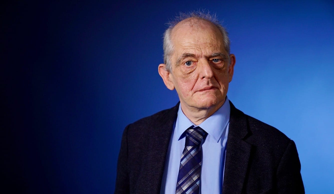 Richard Herzinger is pictured as an elderly man. He is white. He wears a suit and tie. 