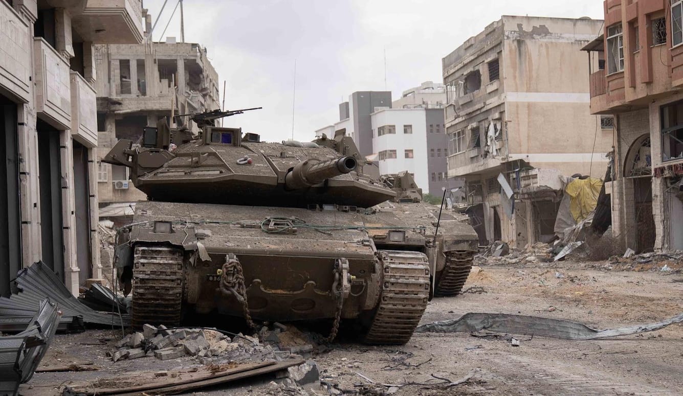 A couple of tanks parked in a ruined city street. 