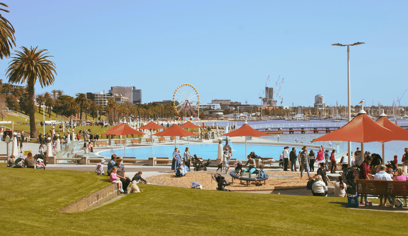 A group of people sitting on top of a lush green field on the seaside. 