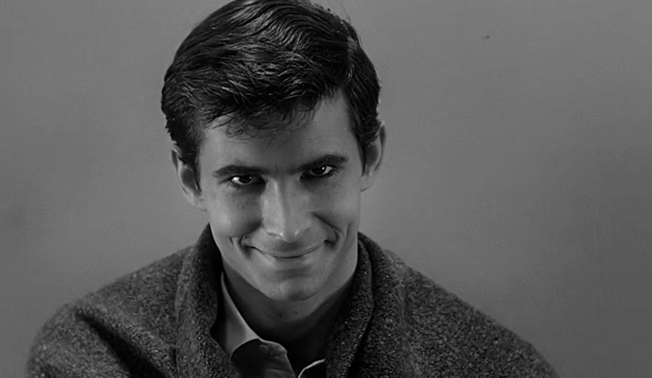 Black-and-white close-up portrait of a young man with short dark hair, wearing a jacket and shirt, facing the camera with a slight smile.