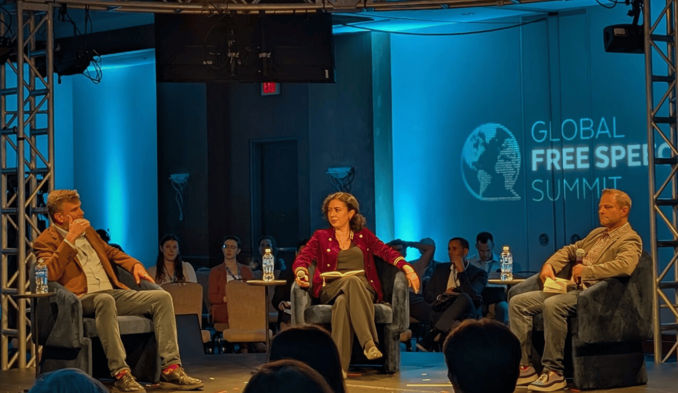 Panel of Ashkhen Kazaryan speaks with Greg Lukianoff and Kevin Goldberg seated onstage in discussion at the Global Free Speech Summit before an audience.